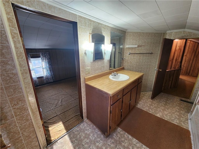 bathroom with tile walls, tile patterned floors, vanity, and crown molding