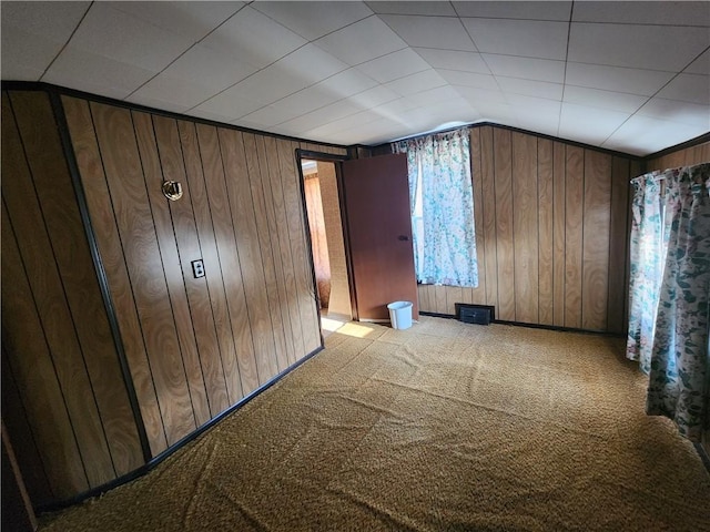 unfurnished bedroom featuring light colored carpet, wooden walls, and vaulted ceiling