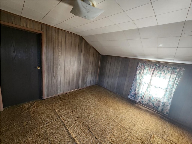 additional living space featuring lofted ceiling, wooden walls, and carpet flooring