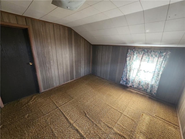 bonus room with vaulted ceiling, wooden walls, and carpet