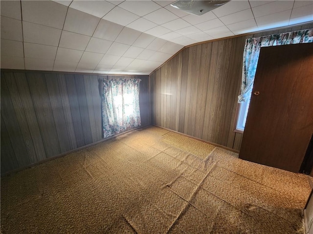 bonus room with wood walls, lofted ceiling, and carpet floors