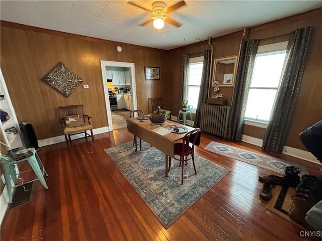 office area featuring wooden walls, a ceiling fan, baseboards, radiator heating unit, and hardwood / wood-style flooring