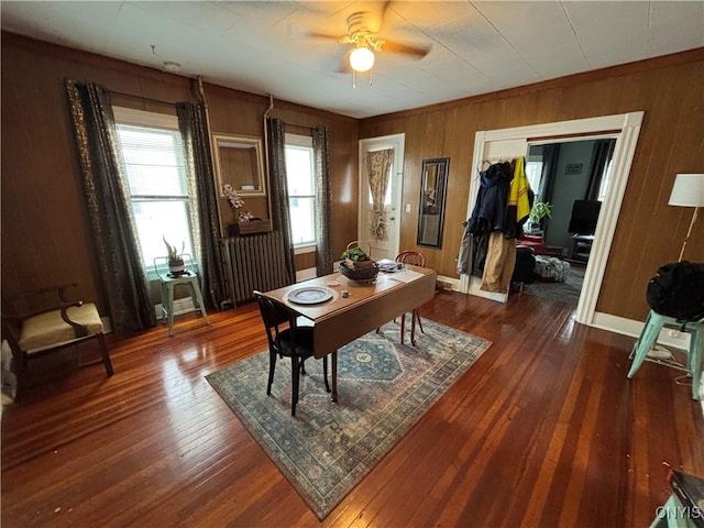 office area with wooden walls, dark wood-style floors, baseboards, and ceiling fan