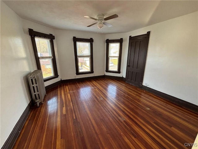 spare room with ceiling fan, baseboards, radiator, and dark wood-style floors