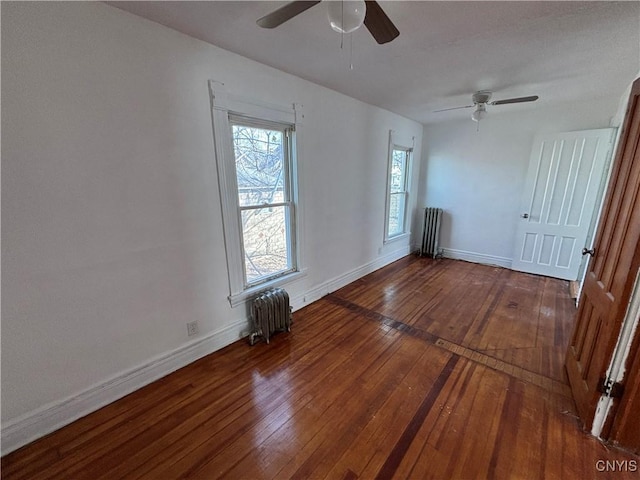 spare room featuring radiator, baseboards, and hardwood / wood-style floors