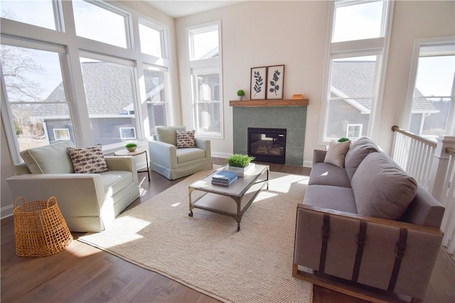 living room featuring a fireplace, a high ceiling, baseboards, and wood finished floors