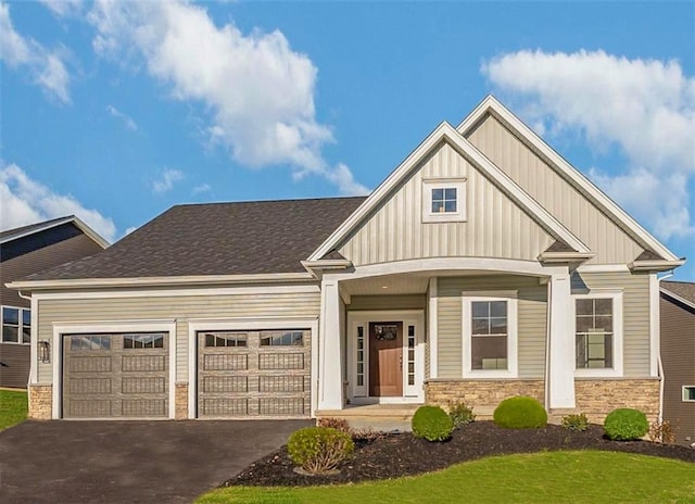 craftsman-style home featuring aphalt driveway, stone siding, an attached garage, and board and batten siding