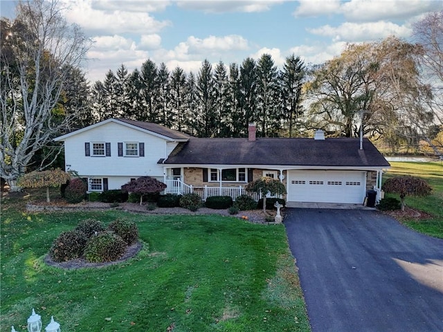 tri-level home featuring a front lawn, driveway, covered porch, a garage, and a chimney