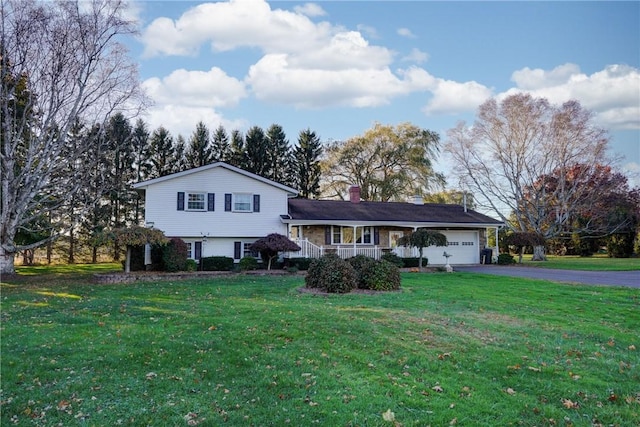 tri-level home featuring a front lawn, driveway, covered porch, an attached garage, and a chimney