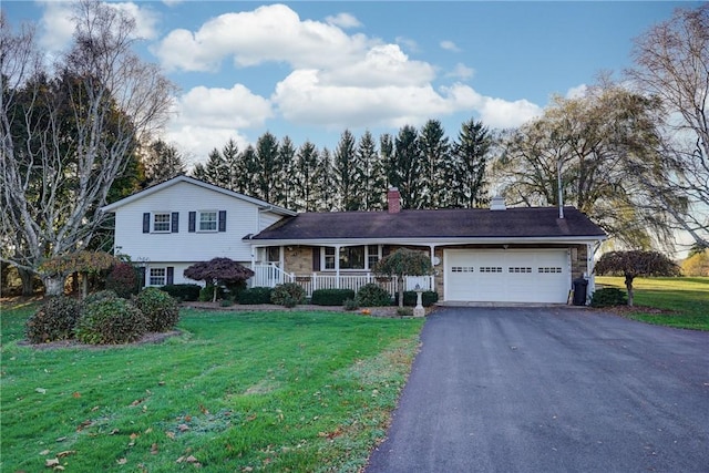 split level home featuring a front yard, a porch, an attached garage, a chimney, and aphalt driveway