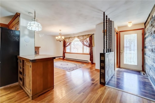 entrance foyer with a baseboard heating unit, an inviting chandelier, and light wood-style flooring