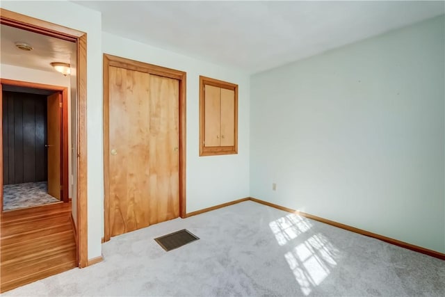 unfurnished bedroom featuring visible vents, baseboards, carpet, and a closet