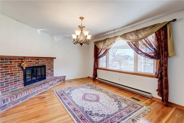 living room with a chandelier, a brick fireplace, wood finished floors, and a baseboard radiator