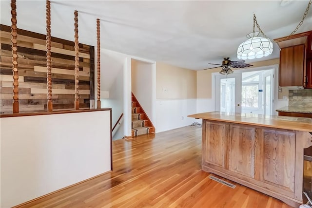 kitchen with visible vents, light wood-type flooring, ceiling fan, and decorative backsplash