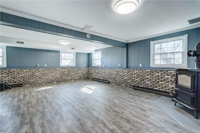 kitchen featuring visible vents, ornamental molding, brick wall, and wood finished floors