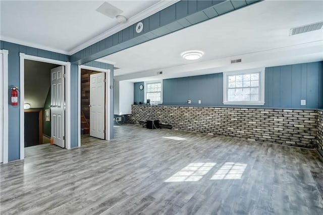 interior space with wood finished floors, visible vents, plenty of natural light, and brick wall