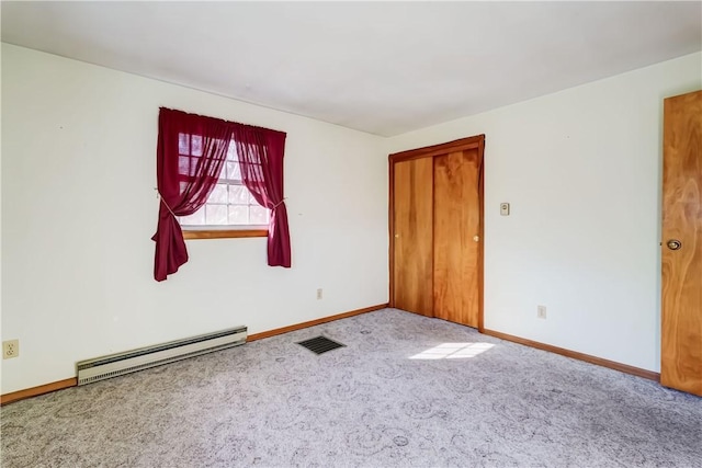 carpeted spare room with visible vents, a baseboard heating unit, and baseboards