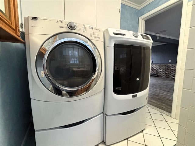 laundry area featuring light tile patterned floors, cabinet space, independent washer and dryer, and ornamental molding