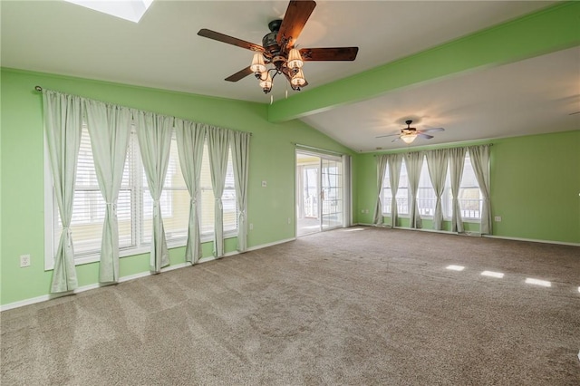 carpeted spare room with baseboards, vaulted ceiling with skylight, and ceiling fan