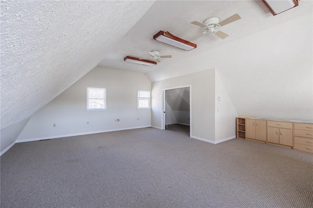 additional living space featuring a textured ceiling, vaulted ceiling, and light carpet