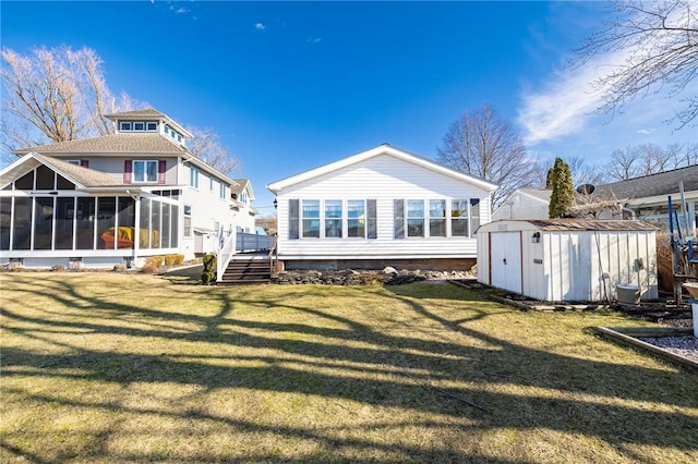 rear view of property with an outbuilding, a lawn, a storage shed, a sunroom, and crawl space