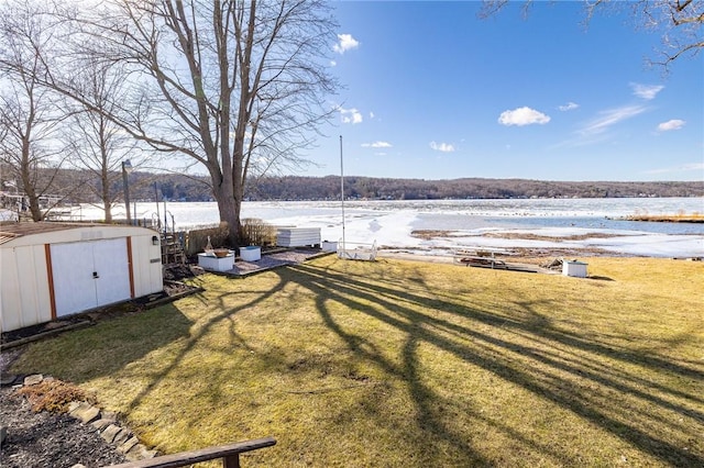 view of yard featuring a storage shed, a water view, and an outdoor structure