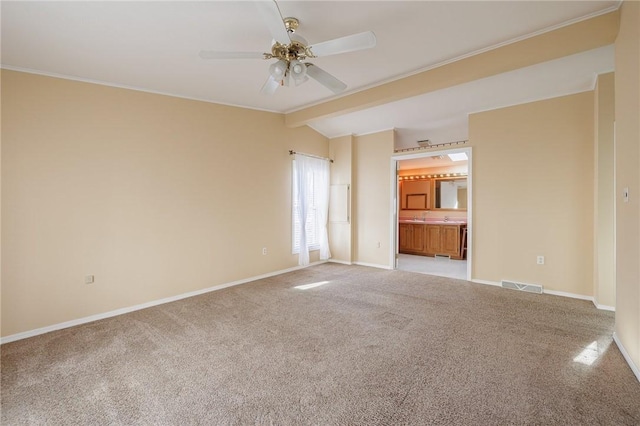 carpeted empty room featuring lofted ceiling with beams, visible vents, baseboards, and a ceiling fan