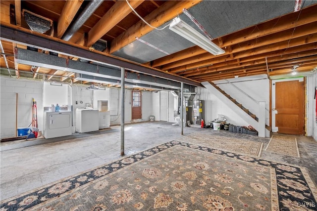 unfinished basement featuring stairs, concrete block wall, water heater, and washing machine and clothes dryer