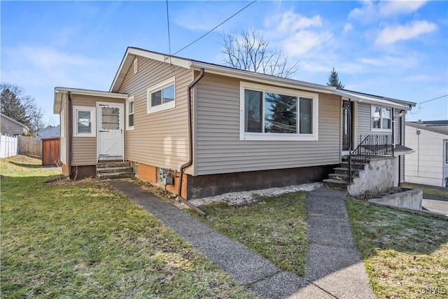 bungalow-style house featuring entry steps, a front lawn, and fence