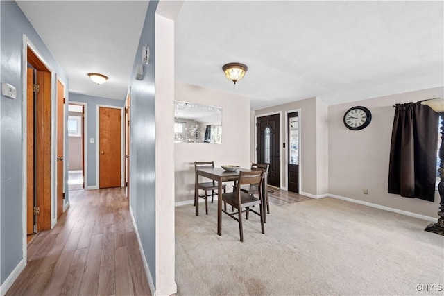 carpeted dining room featuring wood finished floors and baseboards