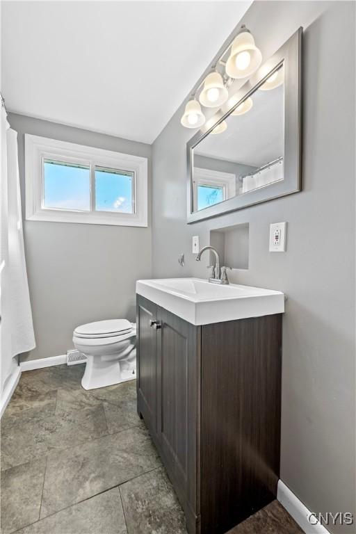 full bath featuring vanity, toilet, and baseboards