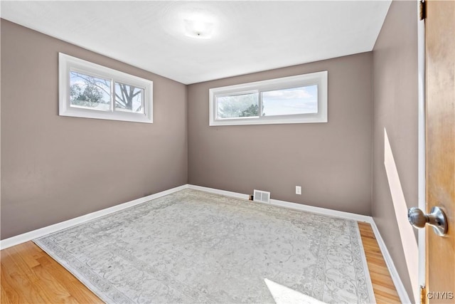 spare room featuring baseboards, visible vents, and light wood finished floors