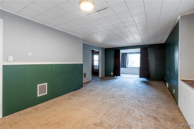 spare room with visible vents, wainscoting, and carpet flooring