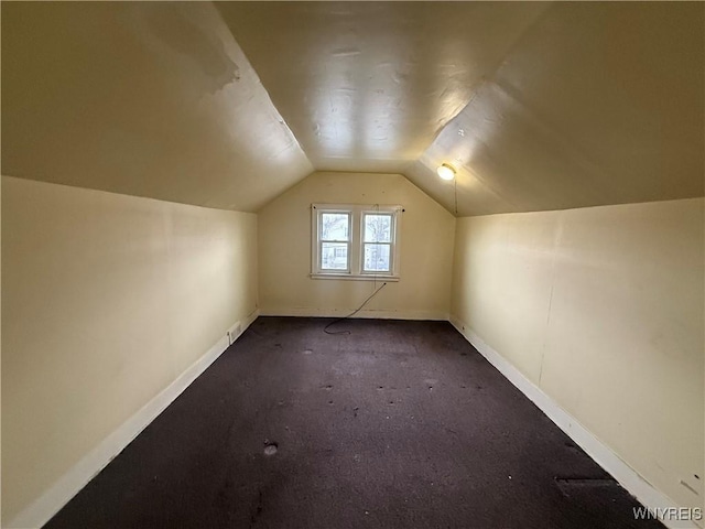 bonus room featuring dark colored carpet, baseboards, and vaulted ceiling