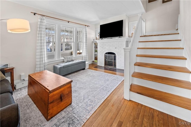 living area featuring stairway, baseboards, a fireplace, and hardwood / wood-style flooring