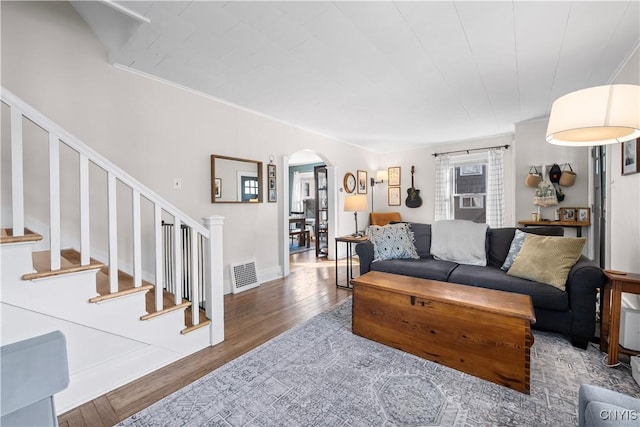 living area featuring stairway, wood finished floors, visible vents, baseboards, and arched walkways