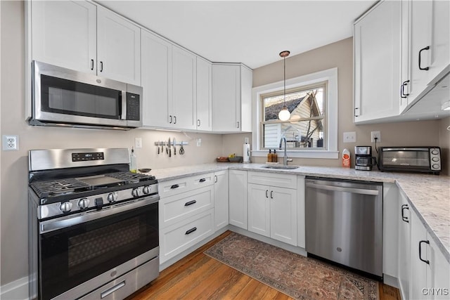 kitchen featuring a sink, appliances with stainless steel finishes, wood finished floors, and white cabinets