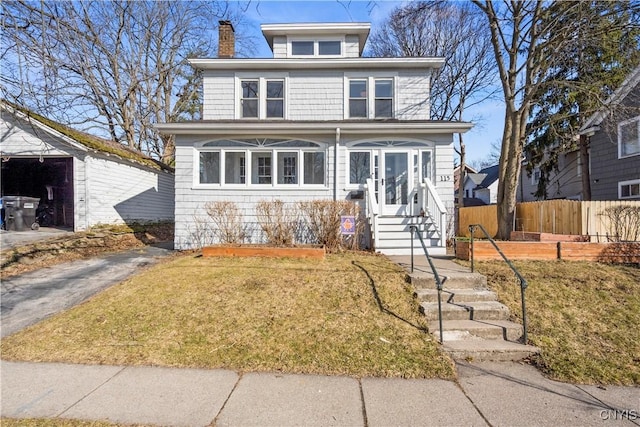 traditional style home featuring entry steps, a front yard, fence, and a chimney