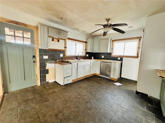 kitchen with backsplash, baseboards, dishwasher, a ceiling fan, and a sink