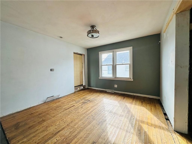 spare room featuring hardwood / wood-style flooring, baseboards, and visible vents