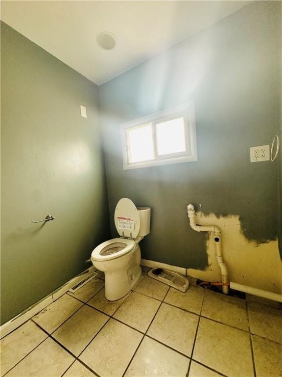 bathroom featuring baseboards, toilet, and tile patterned flooring