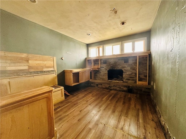 unfurnished living room with wood-type flooring and a stone fireplace