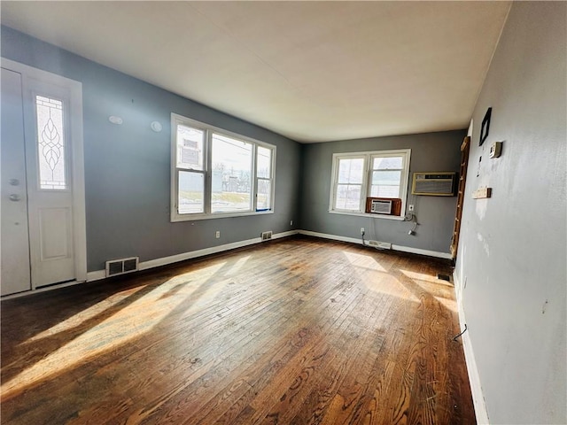 interior space featuring a wall mounted air conditioner, baseboards, visible vents, and wood-type flooring