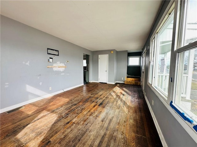 empty room with visible vents, baseboards, and dark wood-style flooring