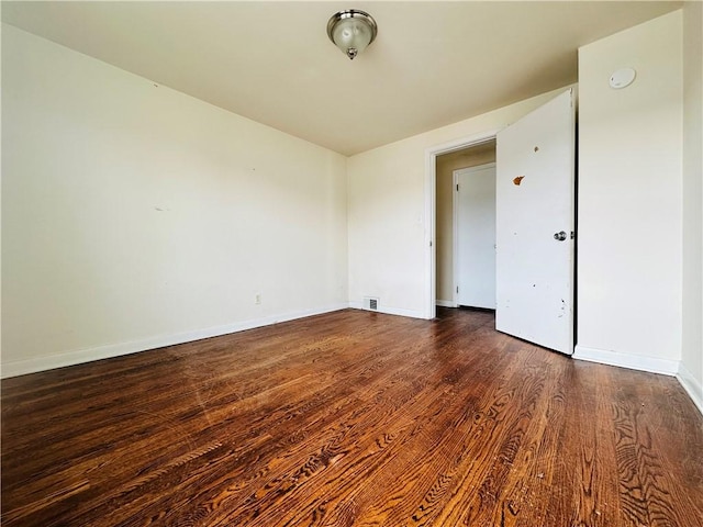 spare room with visible vents, baseboards, and wood finished floors