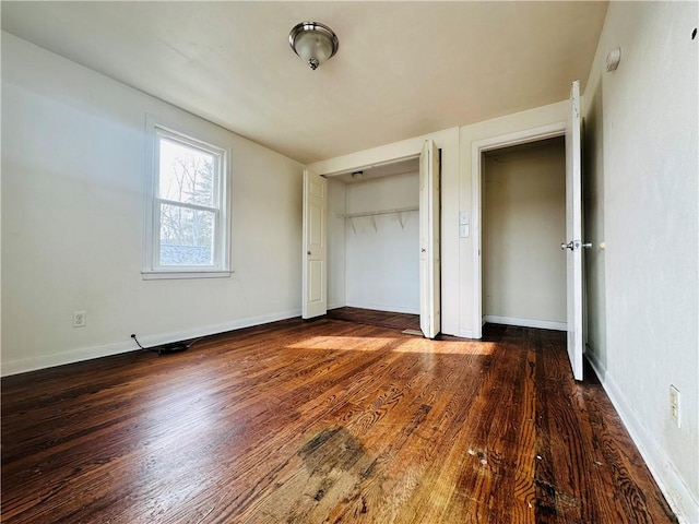 unfurnished bedroom with wood finished floors, a closet, and baseboards