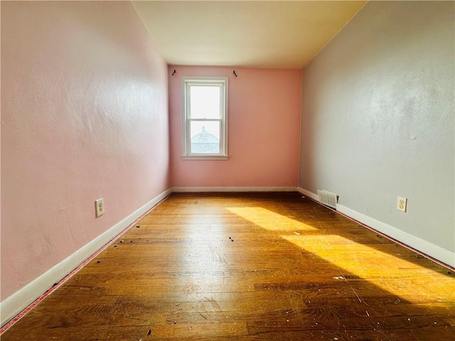 unfurnished room featuring visible vents, wood-type flooring, and baseboards