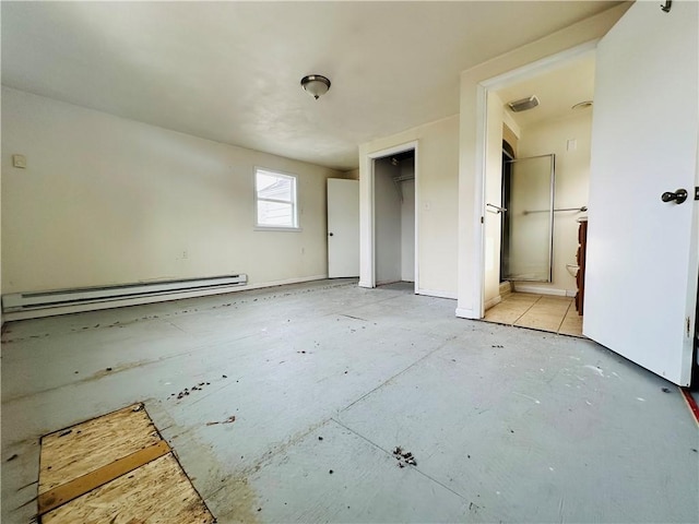 unfurnished bedroom with a closet, ensuite bath, and a baseboard heating unit