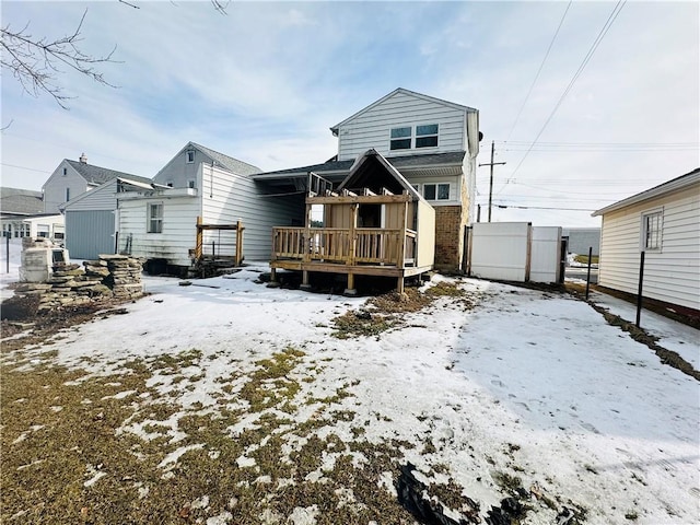 snow covered back of property featuring a deck