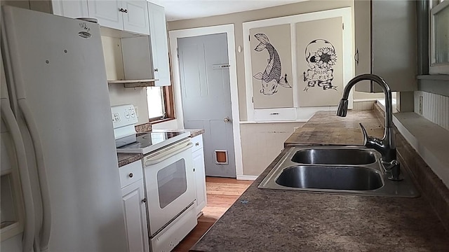 kitchen with white appliances, dark wood-style flooring, a sink, white cabinets, and dark countertops